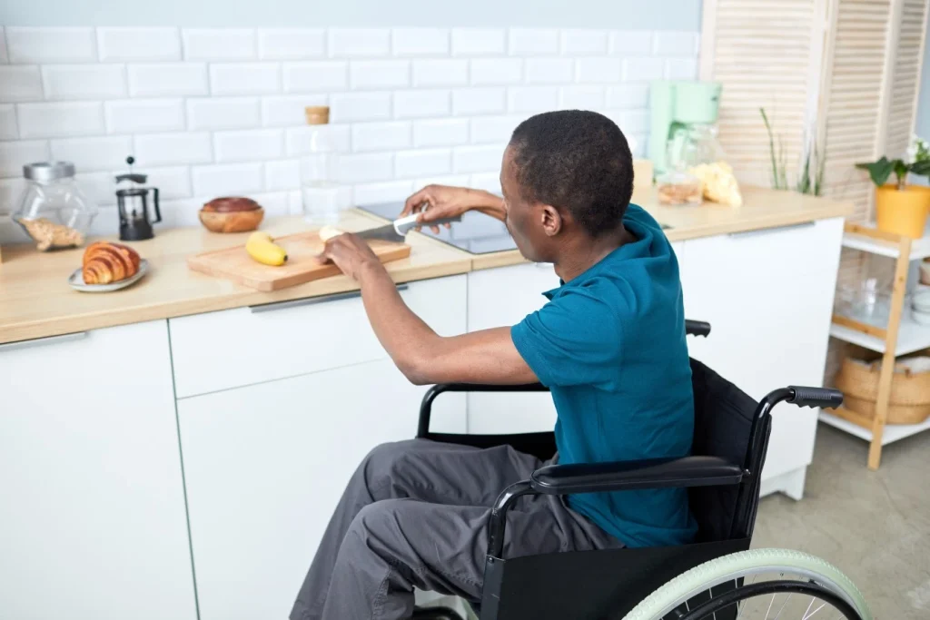 Disabled man in his wheelchair slicing bananas in the kitchen