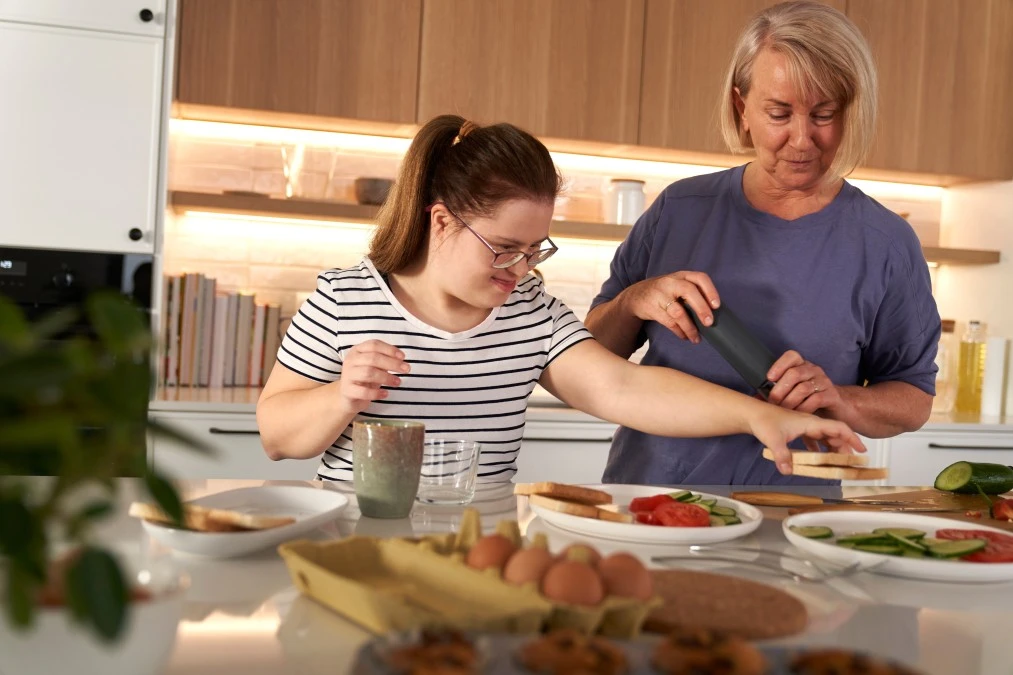 A disabled woman and her support worker cooking in the kitchen